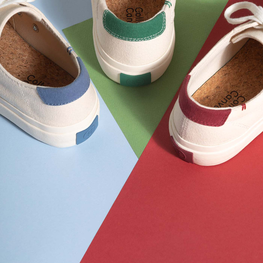Three natural coloured canvas sneakers on multi coloured background of blue, green and red.