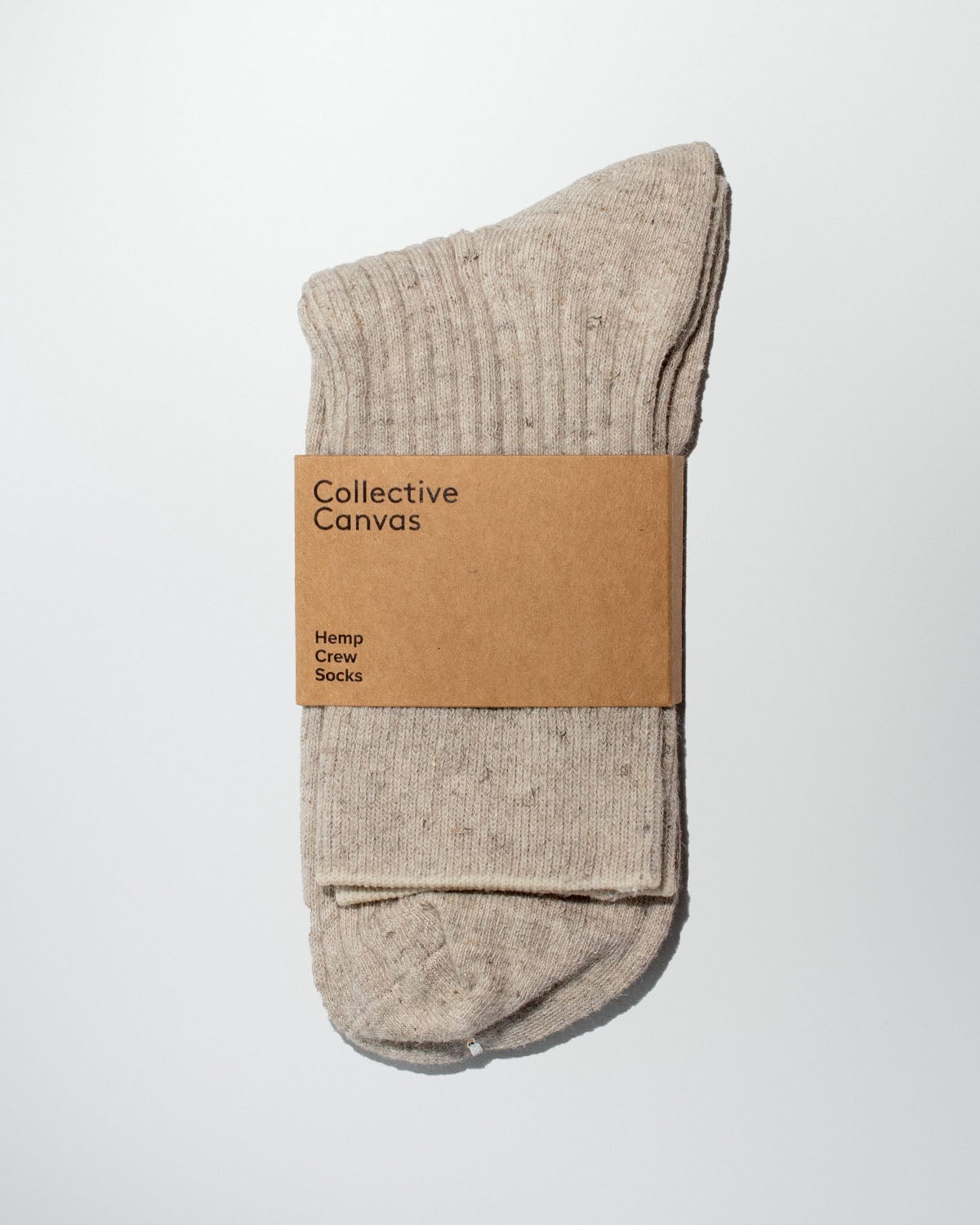 Pair of oatmeal ribbed Hemp Crew Socks with a kraft paper Collective Canvas band